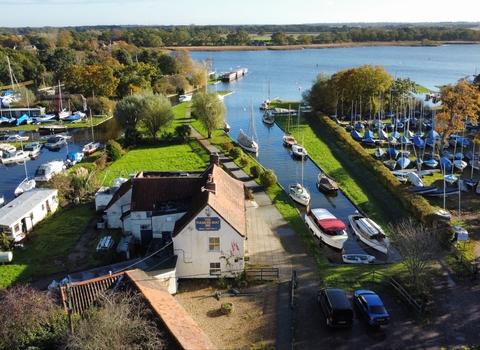 An aerial view of a broad jetty filled with boats, with buildings clustered around the edge