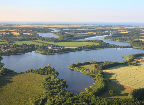 A drone image of a Broad on a sunny day, including patches of green land around it