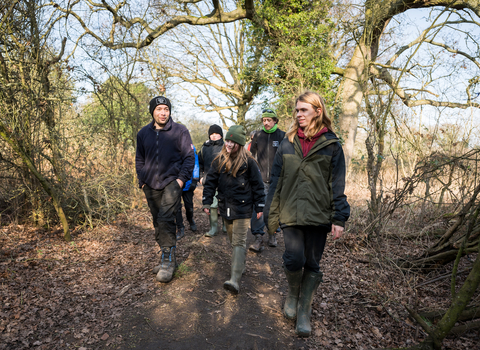 A group of young people walking with reserve manager, Matt, at Sweet Briar. 