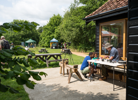 A visitor and his kid are at Hickling visitor centre looking at moth traps with a volunteer. 