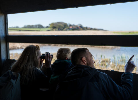 A young family peering out of a hide at Cley.