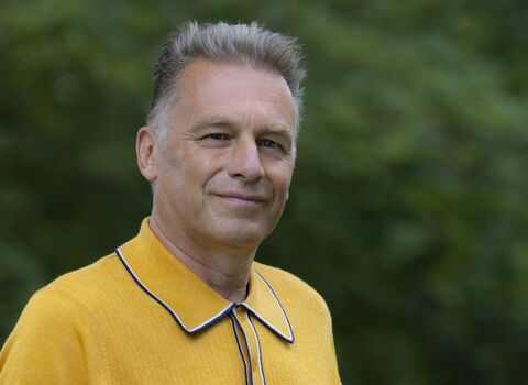 Chris Packham wearing a yellow top and facing the camera