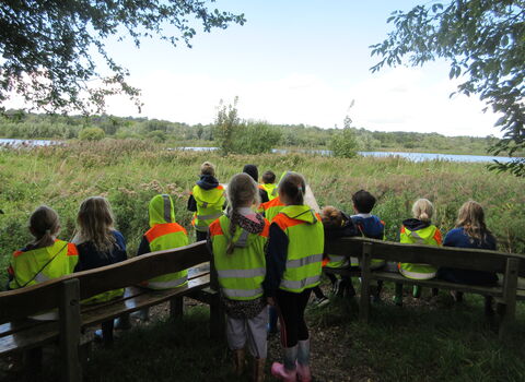 A group of primary school children in high-vis looking out over a nature reserve. 