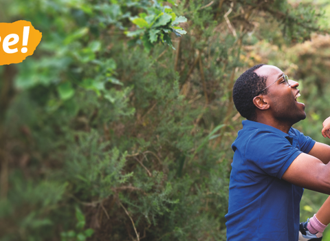 A father picks up his laughing child on a nature walk alongside the text kids go free